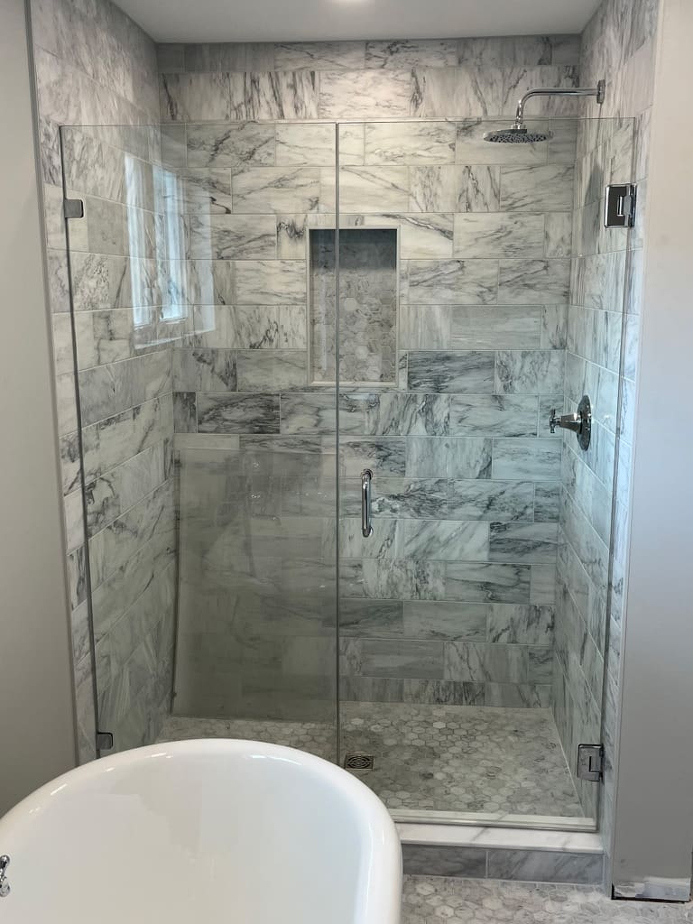 A renovated bathroom with a marble tiled walk-in shower