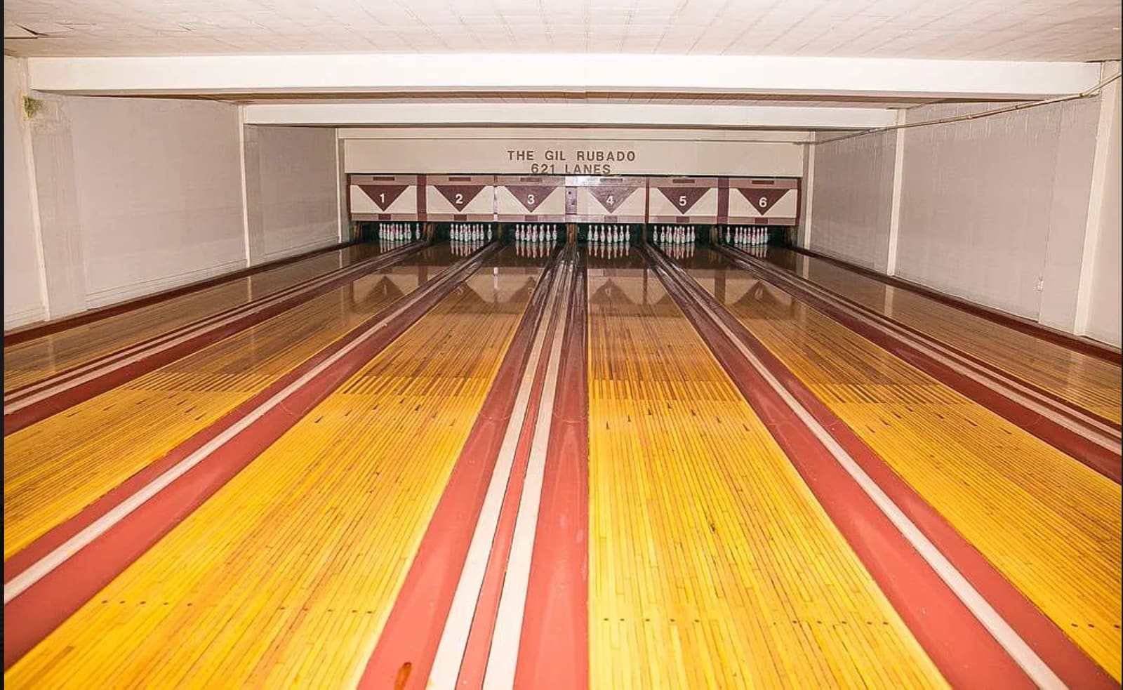 The six-lane bowling alley, pins set, lanes polished