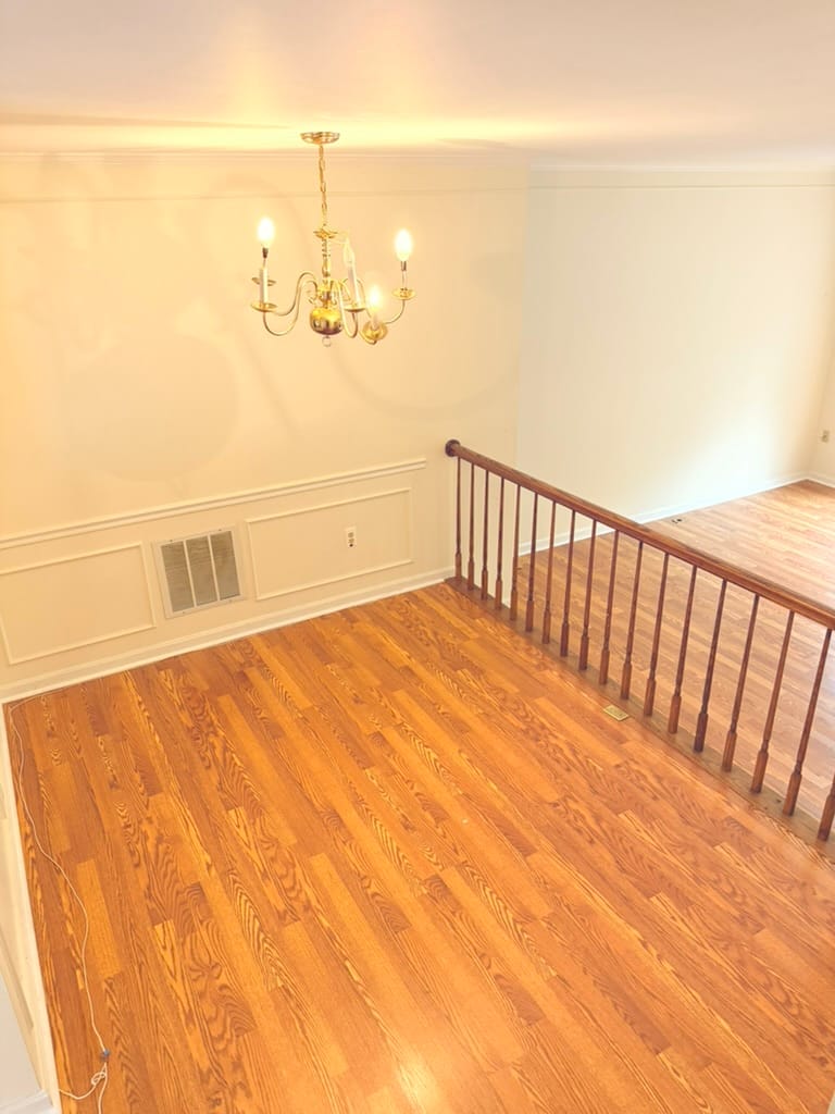 The dining area, empty, with a chandelier and a stair railing along one side